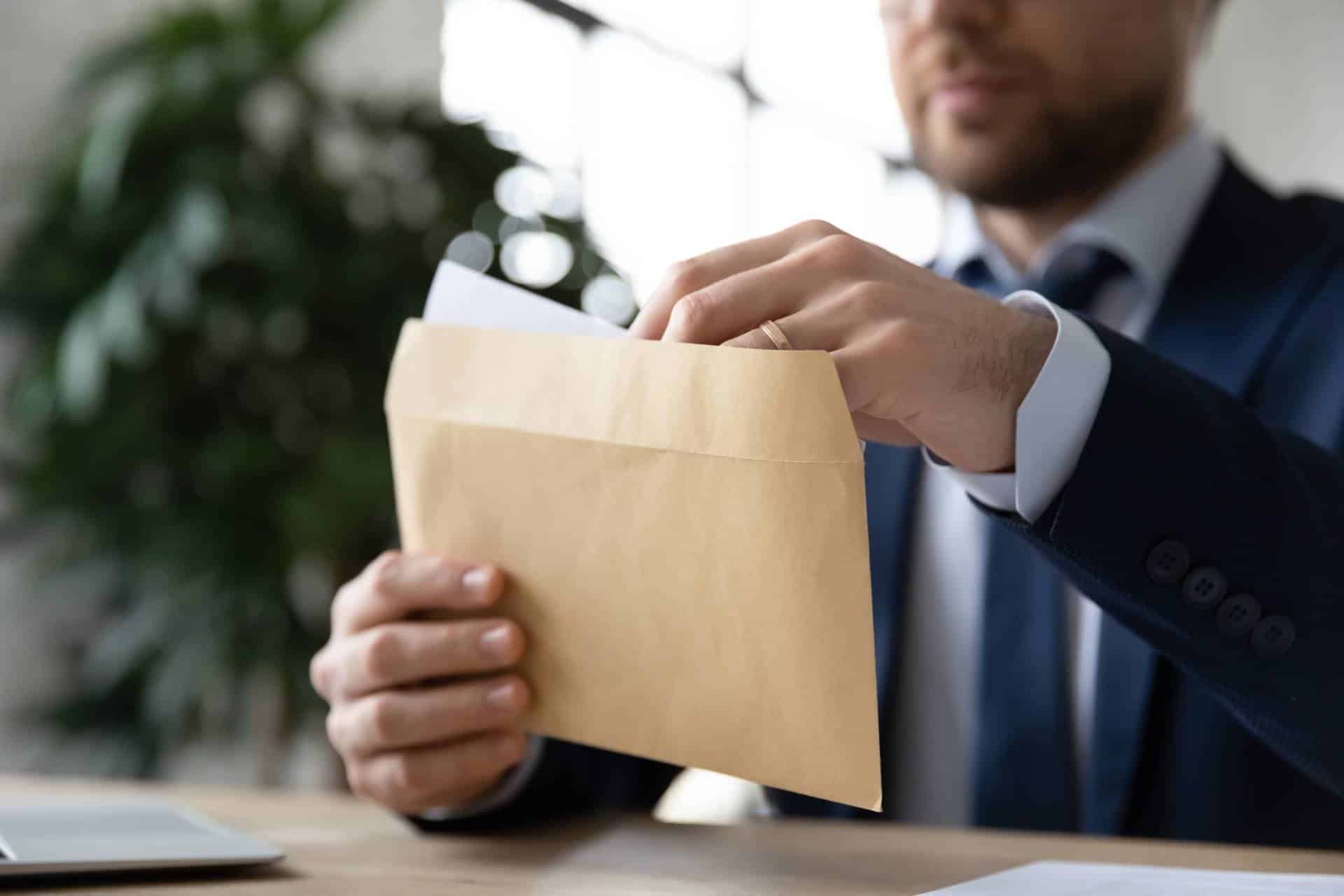 Close up businessman opening paper envelope with letter in office