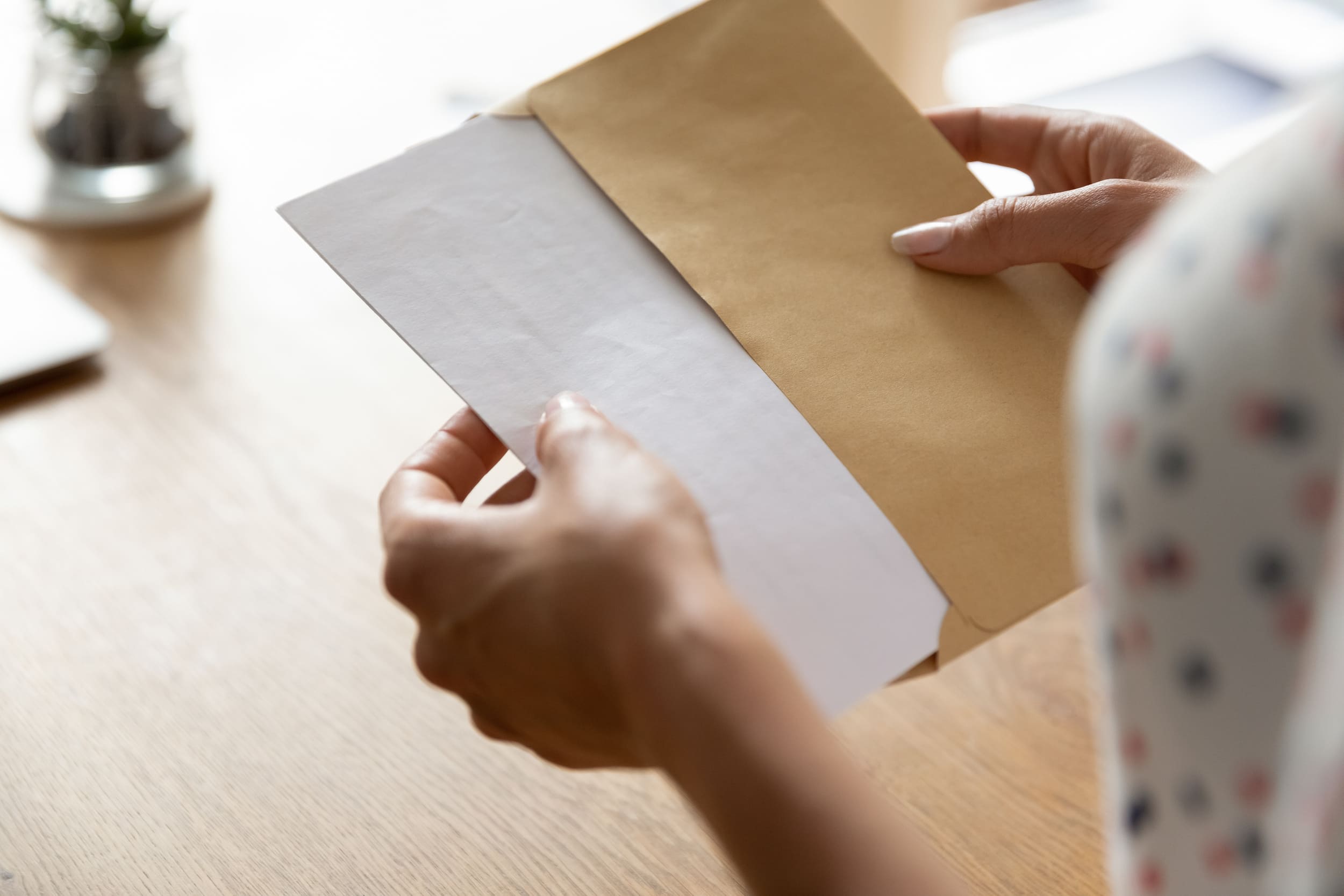 main insérant un courrier plié grâce à une plieuse automatique dans une enveloppe